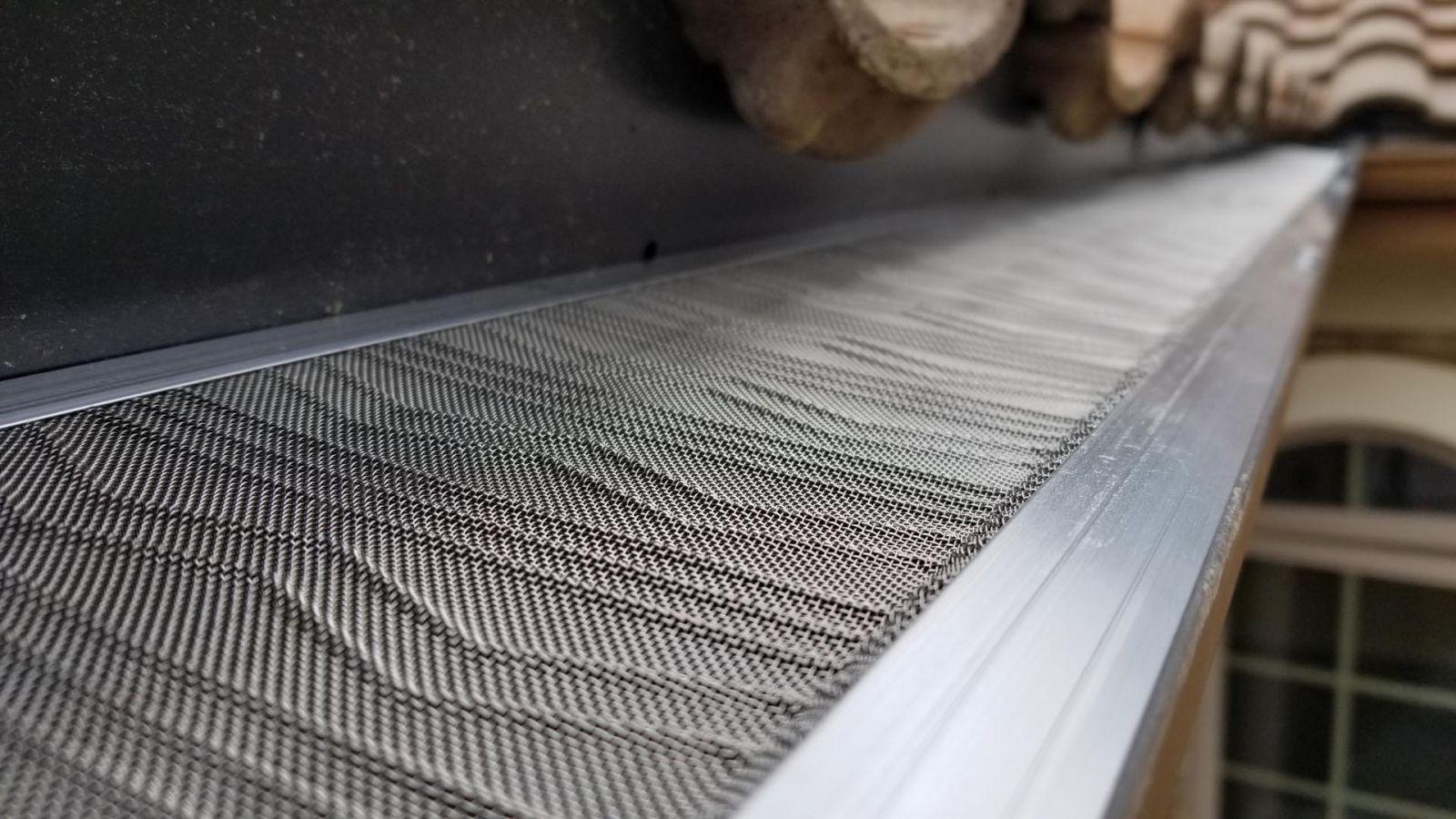 A close up of a gutter with a screen on it.