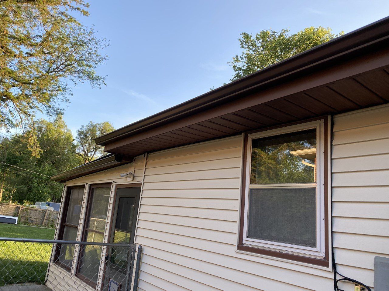 A white house with a brown gutter and a window