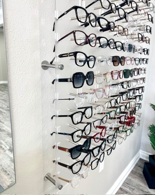 Wall display with many eyeglasses in rows on a neutral wall.