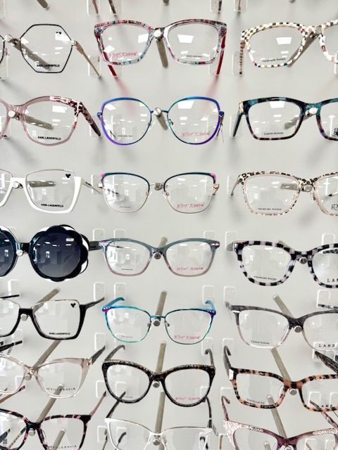Glasses displayed on a white rack. Various frame styles and colors are shown.