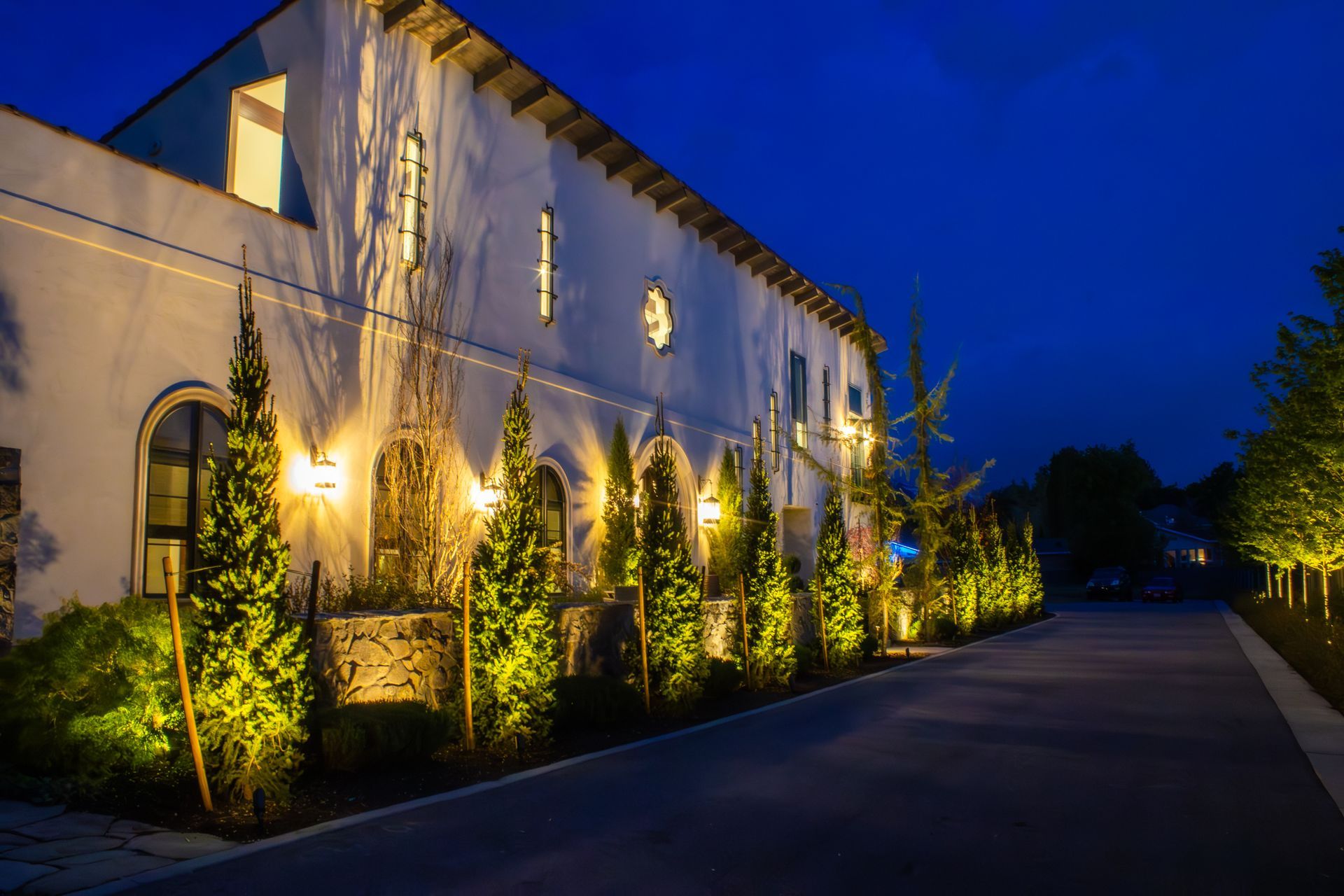 A garden is lit up at night with a house in the background.