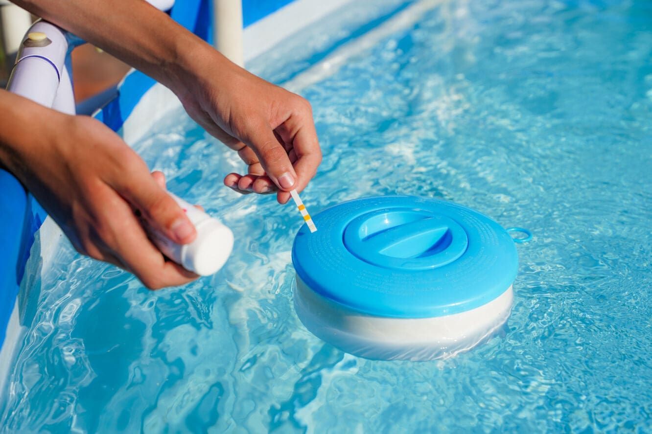 Person Testing Pool Water With a Test Strip and Chemicals by a Floating Dispenser — PUMPtek in Grovedale, VIC