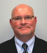 A smiling doctor in a lab coat with a stethoscope around his neck.