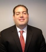 A smiling doctor in a lab coat with a stethoscope around his neck.