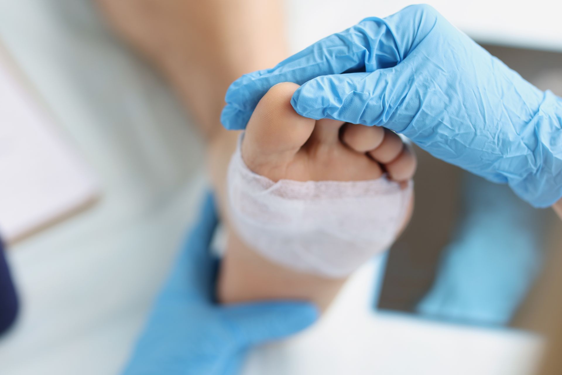 A person's foot being bandaged by gloved hands in a medical setting.