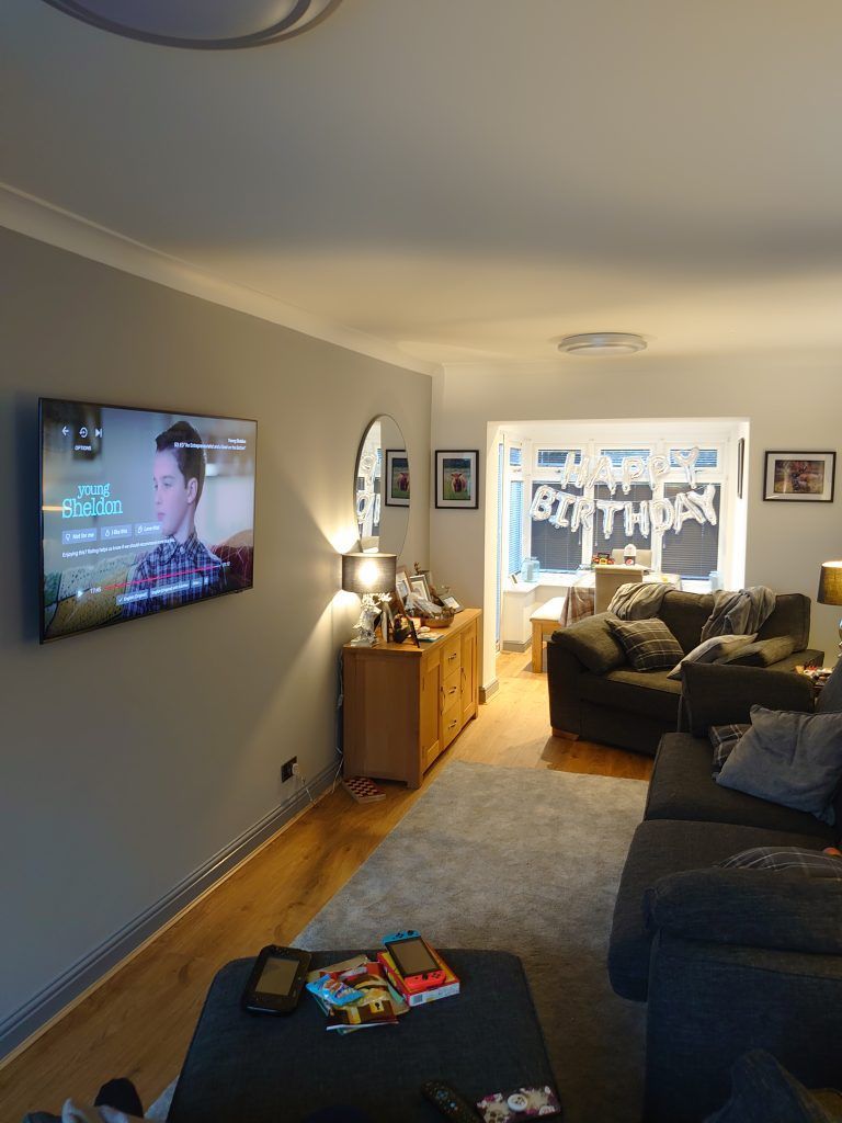 A living room with a wall-mounted TV, a wooden cabinet, gray sofas, and 