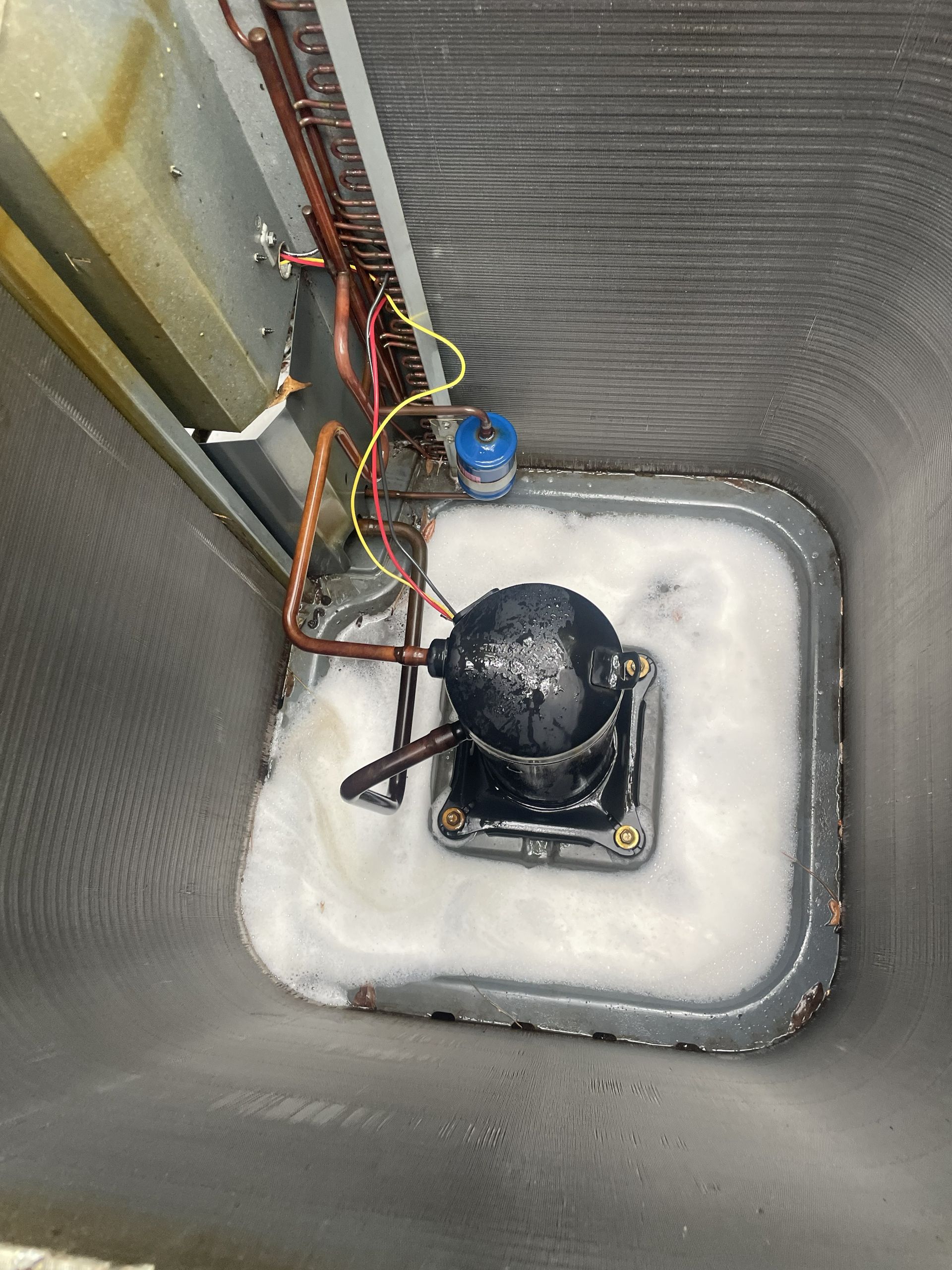 HVAC technician's digital manifold gauge set connected to an outdoor air conditioning unit at night.