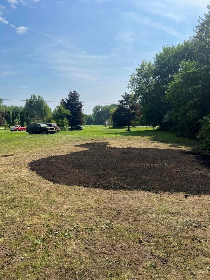 A Large Pile of Dirt Is in the Middle of a Grassy Field — St. Charles, MI — Acorn Tree Service & Landscape Inc