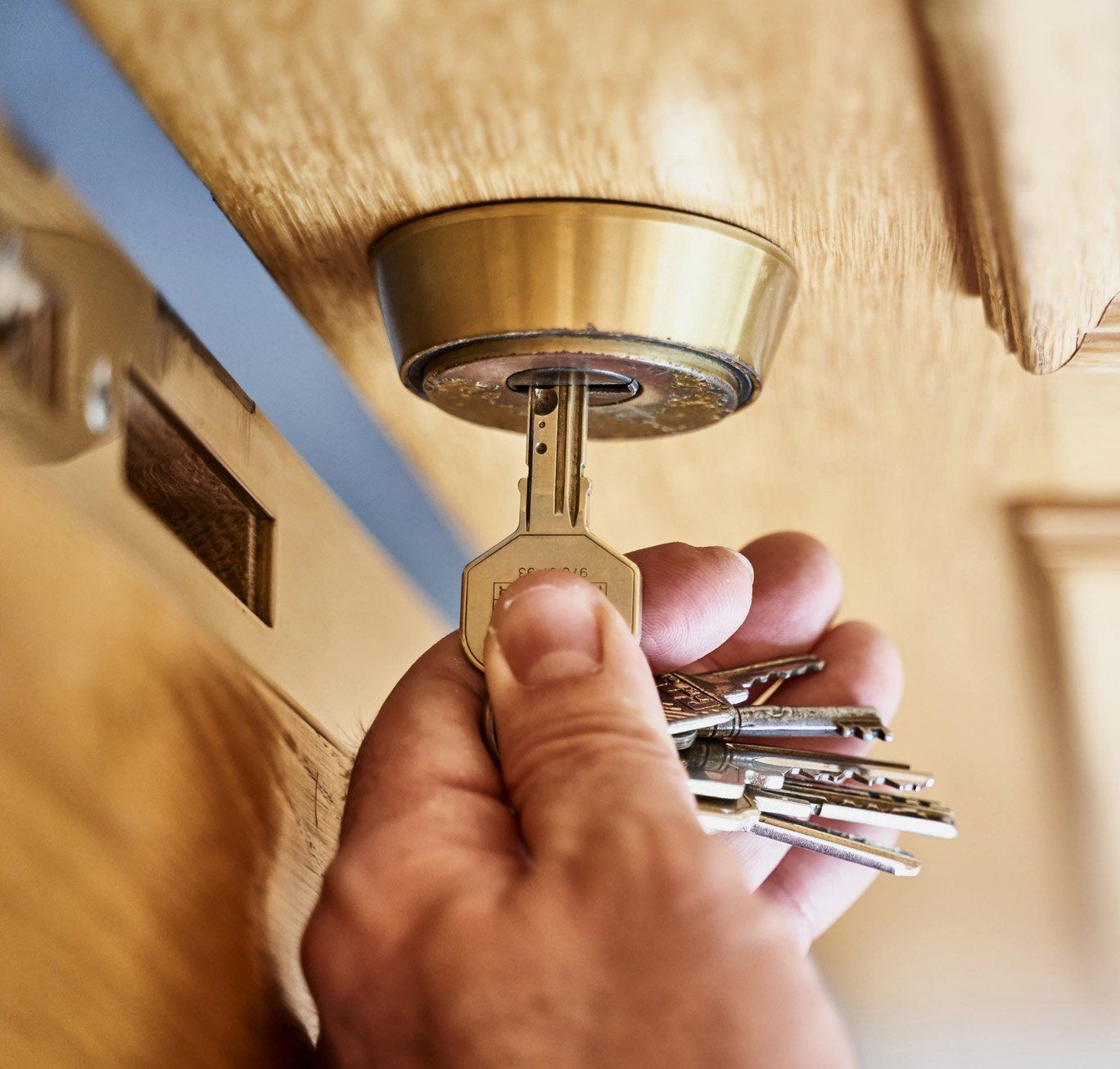 Hand with key opening a wooden door | Shepparton, VIC | Solar City Locksmiths
