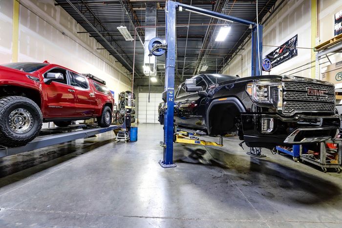 Trucks On Hydraulic Lifts Inside Service Bay | G & M Motorsports