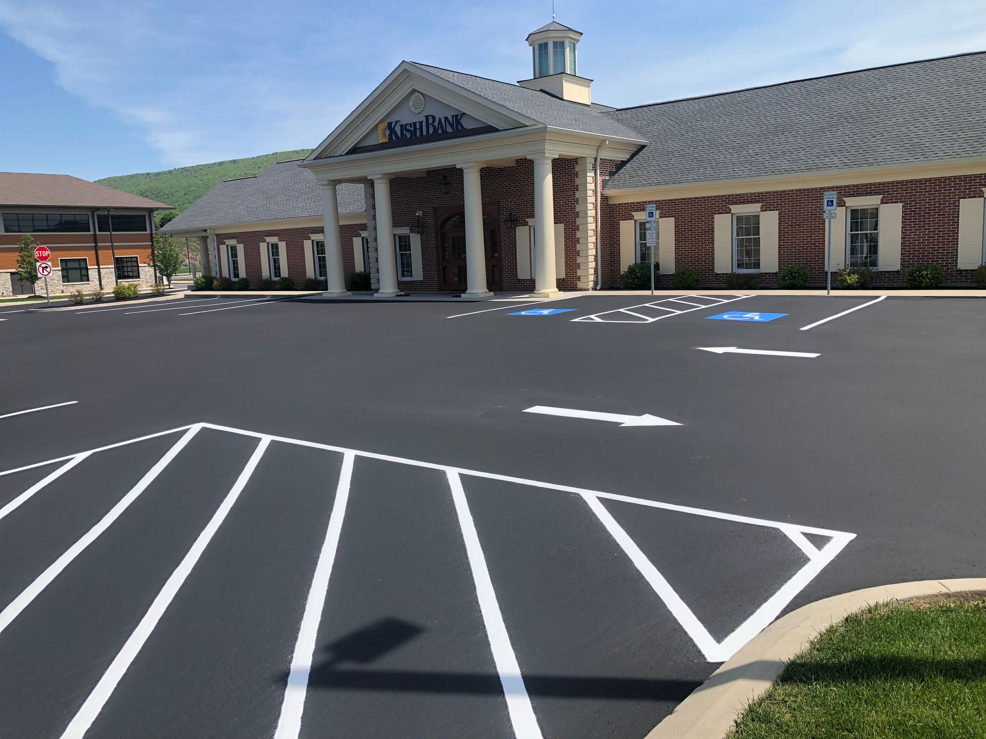 Paved parking lot in front of a brick building with columns.