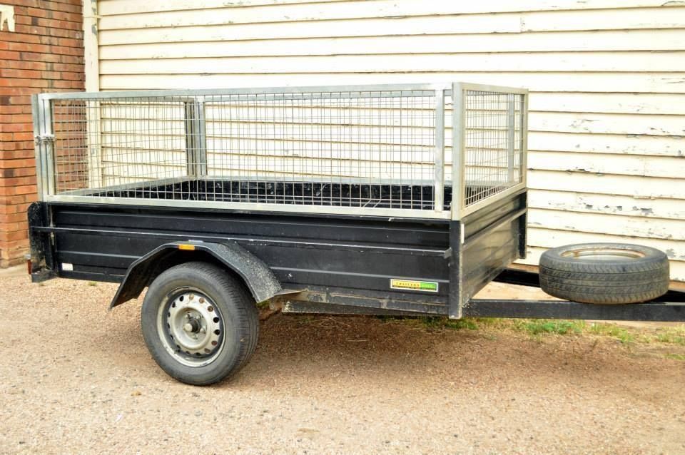 A Black Trailer is Parked in Front of a White Building — Locqal Car Truck Trailer Rentals in Emerald, QLD