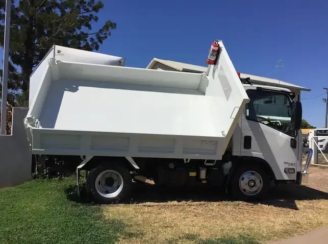 A White Dump Truck is Parked in the Grass in Front of a House — Locqal Car Truck Trailer Rentals in Emerald, QLD