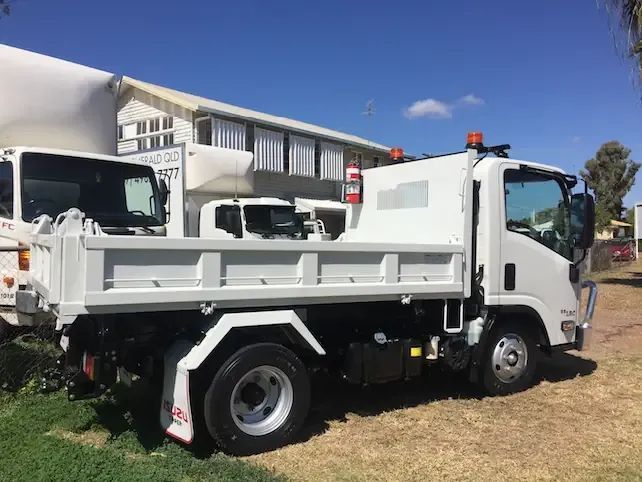 A White Dump Truck is Parked in Front of a Building — Locqal Car Truck Trailer Rentals in Emerald, QLD