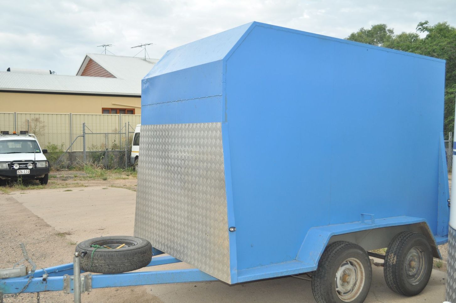 A Blue Trailer is Parked in a Parking Lot Next to a White Truck — Locqal Car Truck Trailer Rentals in Emerald, QLD