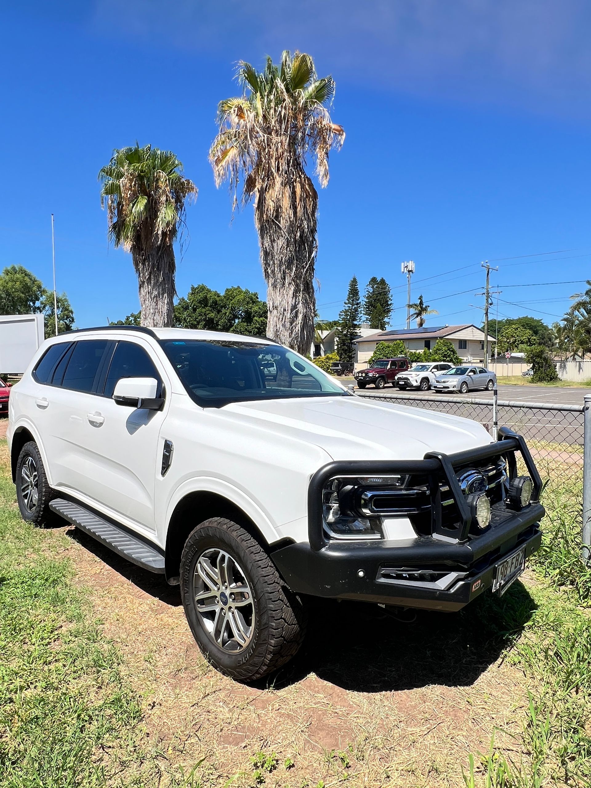 A White Suv is Parked in a Grassy Field With Palm Trees in the Background — Locqal Car Truck Trailer Rentals in Emerald, QLD