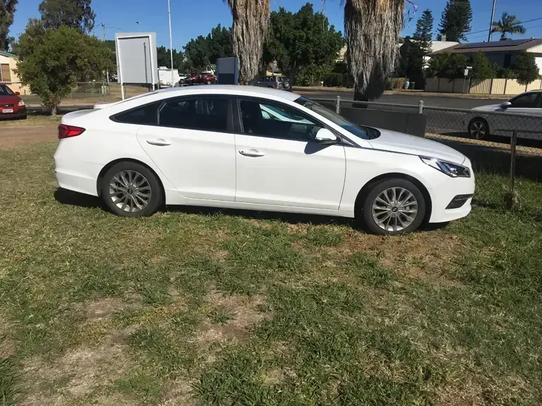 A White Car is Parked in a Grassy Field — Locqal Car Truck Trailer Rentals in Emerald, QLD