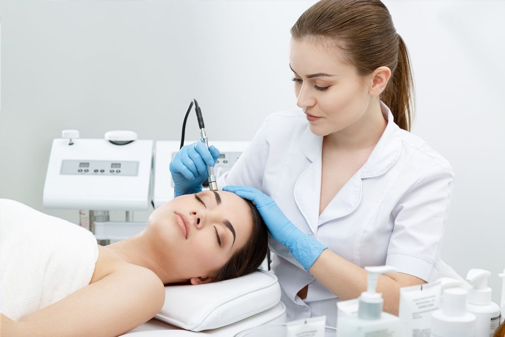 A Professional Uses a Handheld Cosmetic Device — Aura Mediclinic in Ashmore, QLD