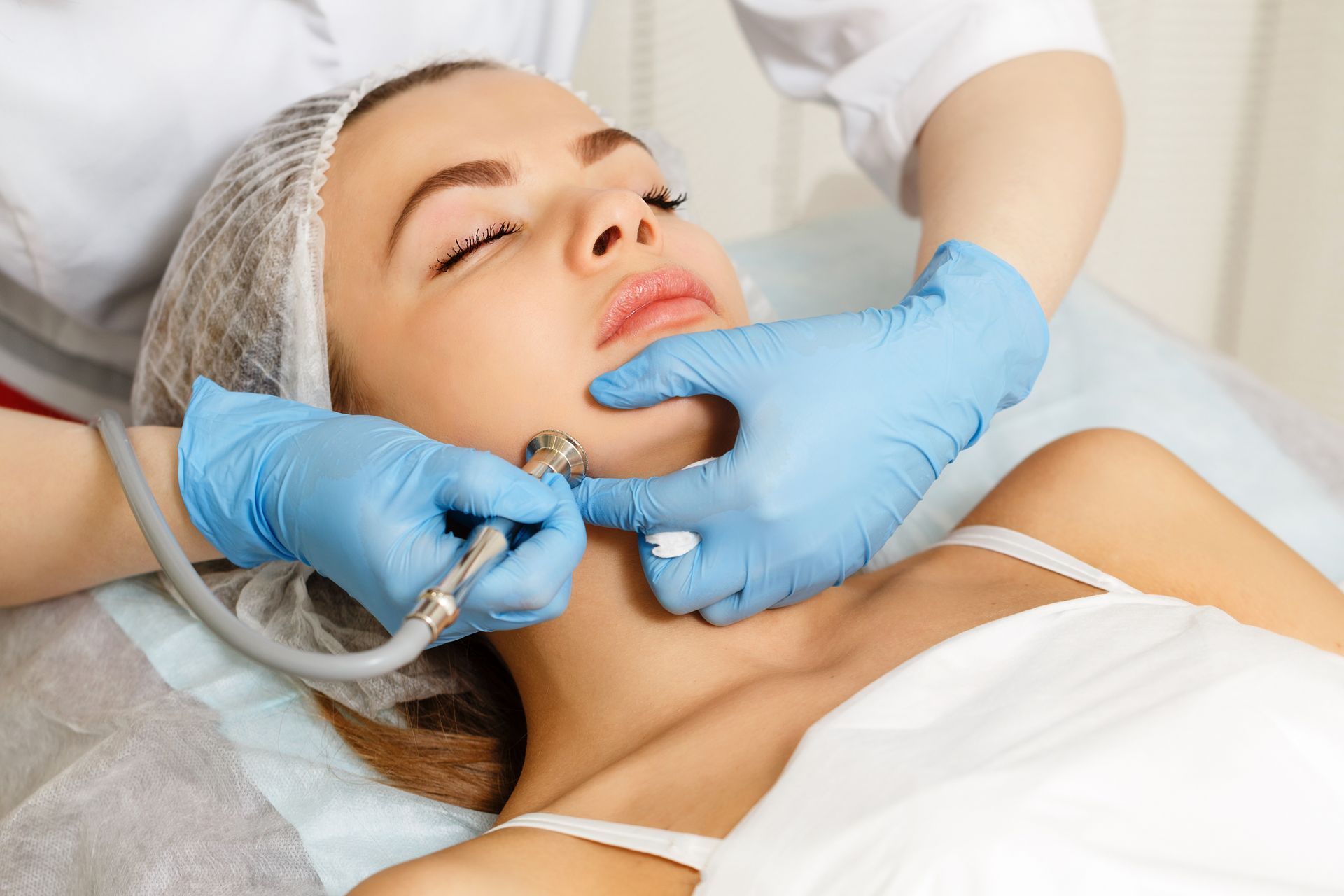 A Beautician in Blue Gloves Performs a Facial Treatment— Aura Mediclinic in Ashmore, QLD
