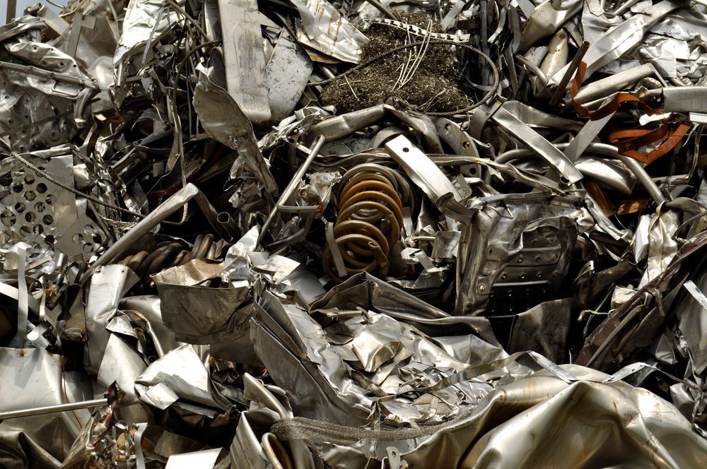 Montón de trozos de metal triturados y brillantes con un resorte visible de color cobre.