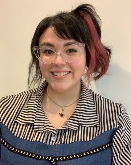 A woman wearing glasses and a striped shirt is smiling for the camera.