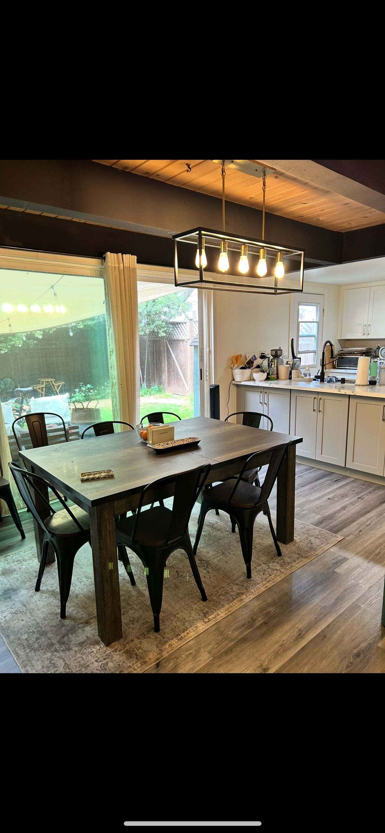 A dining room table with chairs and a chandelier in a kitchen.