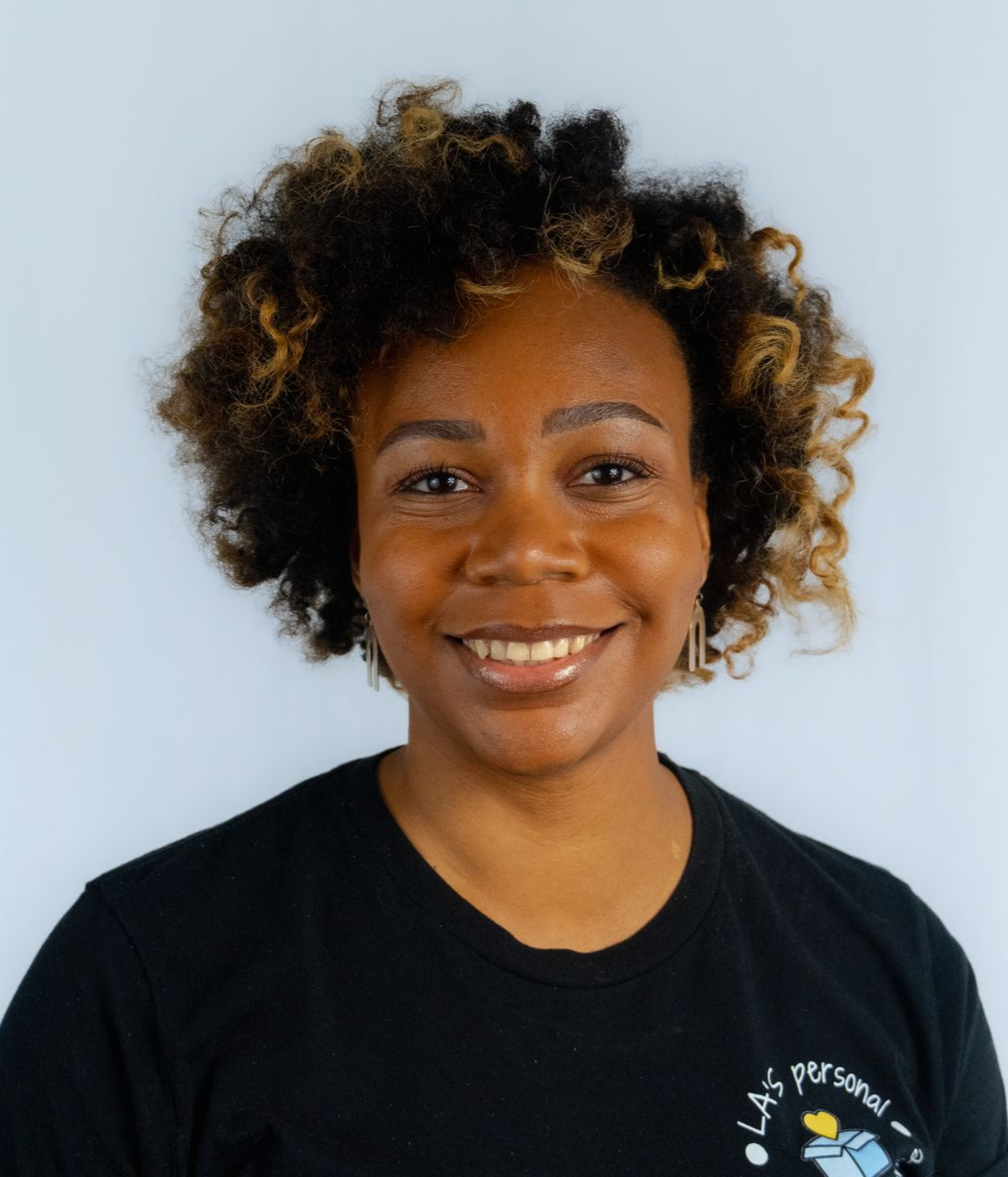Smiling woman in yellow top, sunglasses atop head, on a boat. Water and docks visible in background.