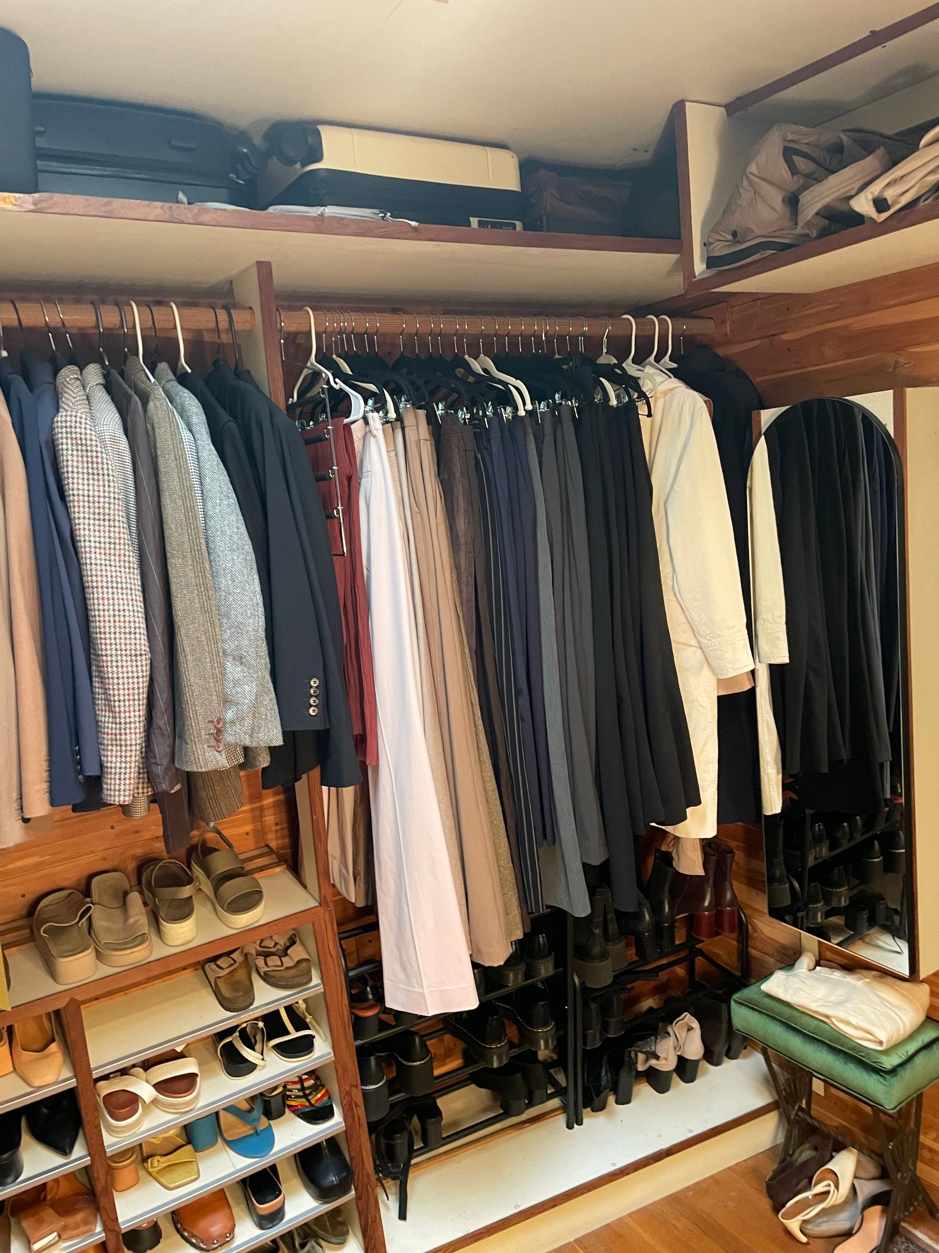 Closet with clothes hanging on rods and shoes on shelves; wood shelves and trim.