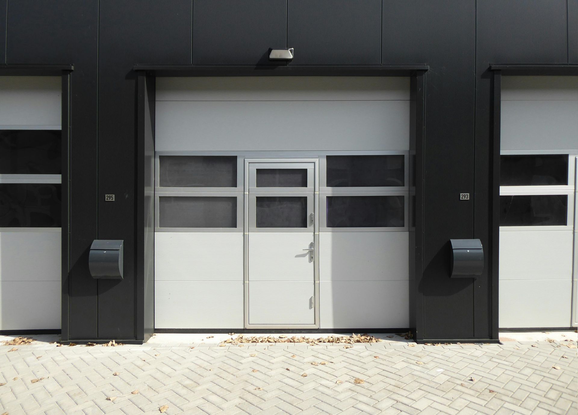 A white garage door is open in front of a black building