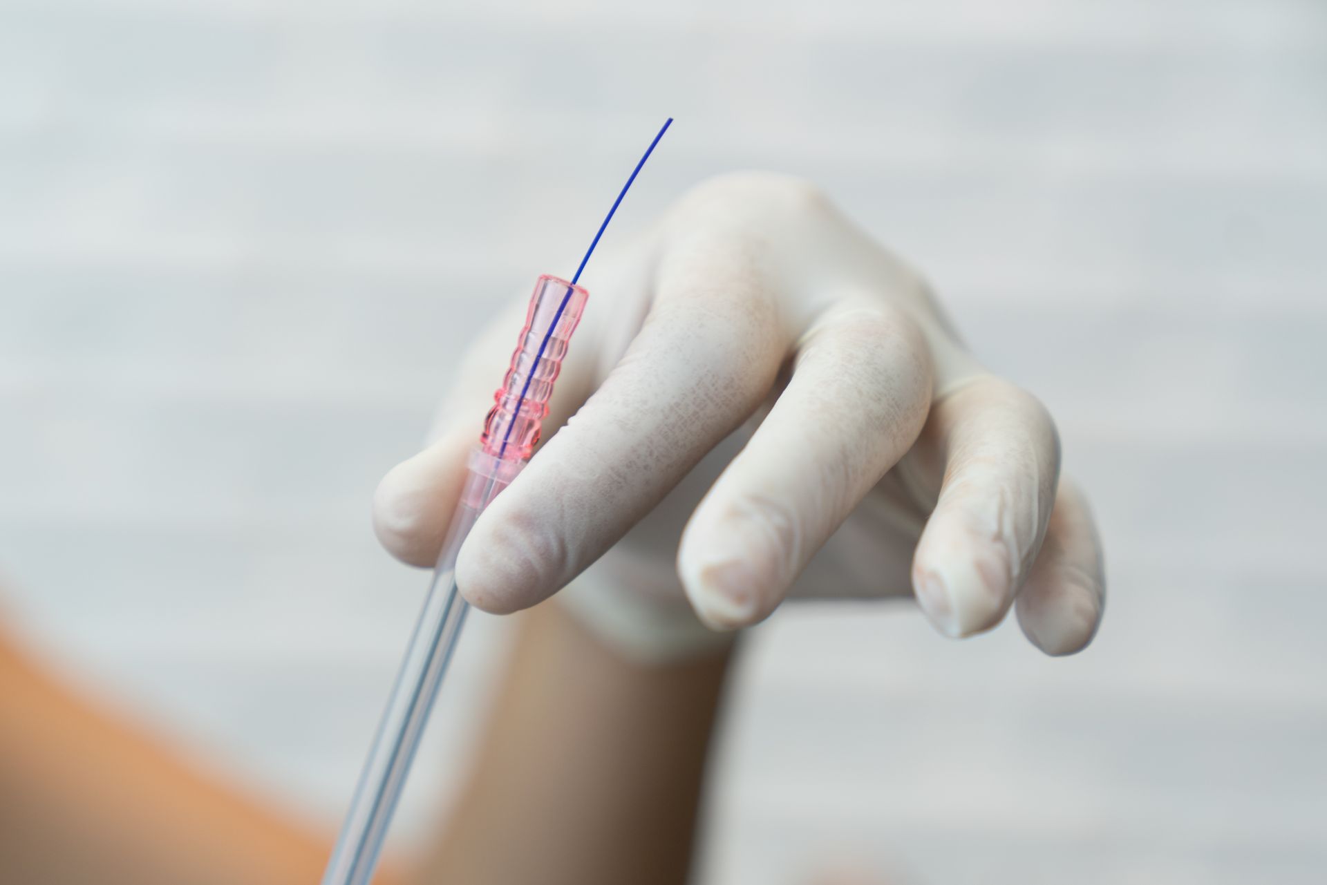 A person wearing gloves is holding a syringe in their hand.