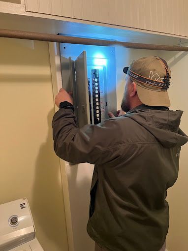 A man is working on a electrical box in a laundry room.