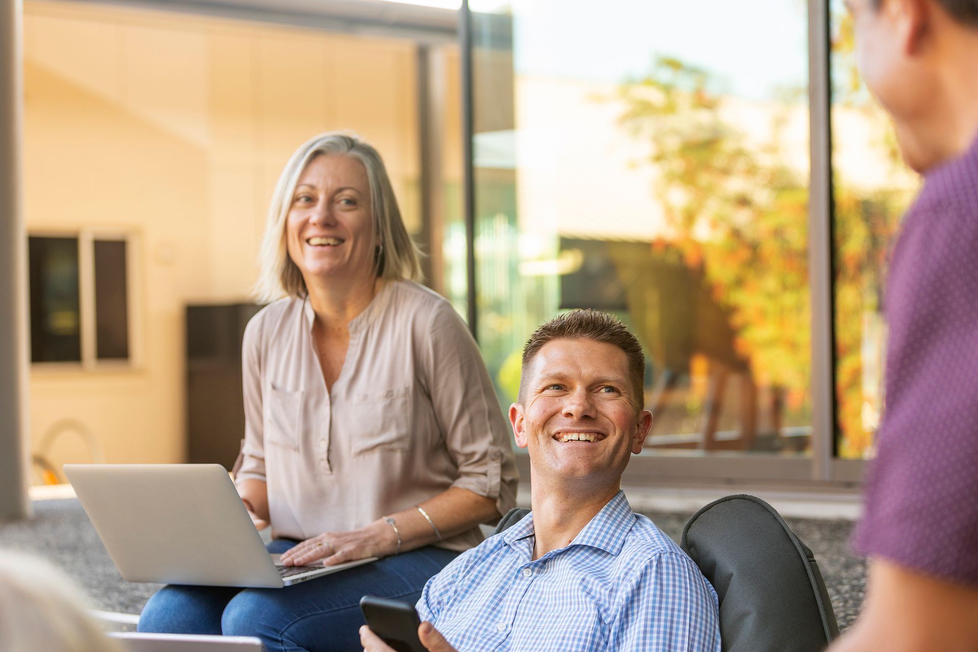 A man and a woman are sitting on a couch with a laptop and a cell phone.