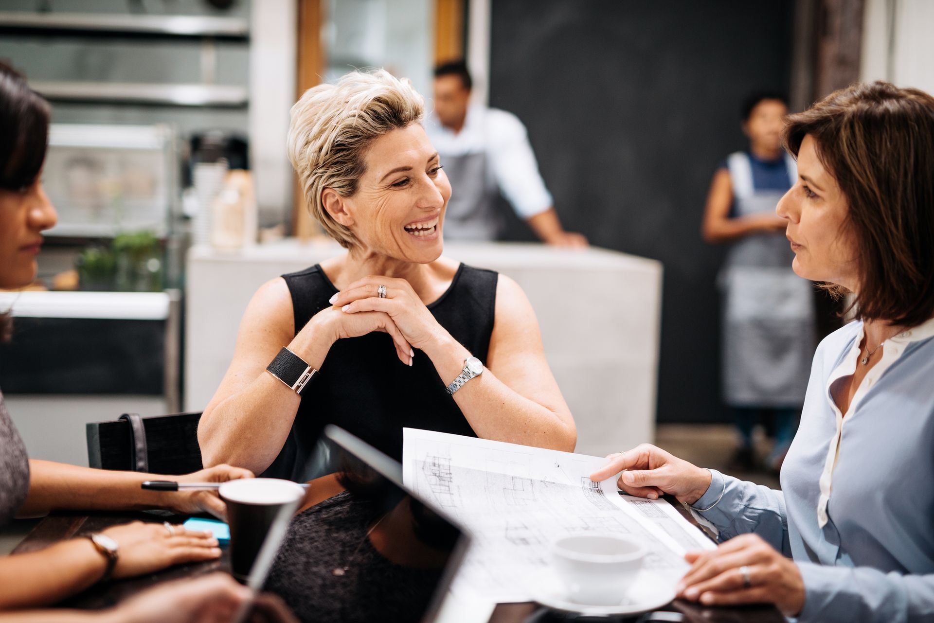 A group of women are sitting at a table in a restaurant talking to each other.