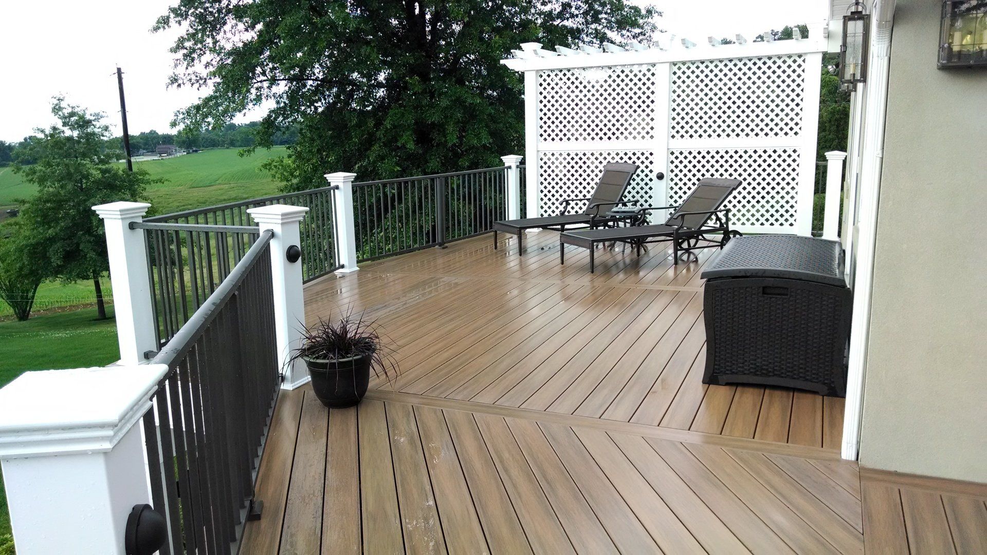 Wooden deck with seating and lattice, overlooking a green landscape.