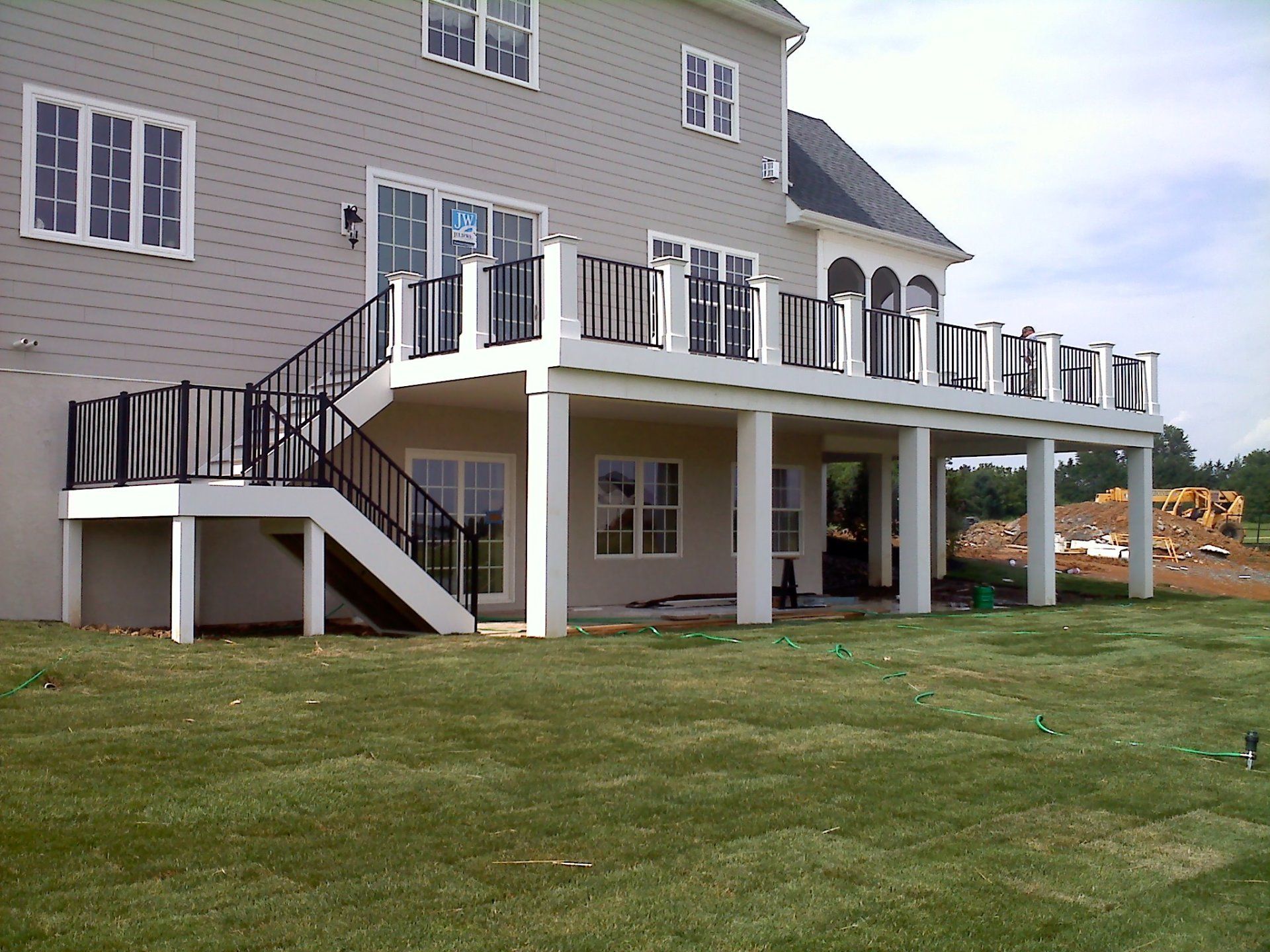 Large white deck with black railings attached to a beige house, overlooking a grassy lawn by Millcreek Fence & Decks in Lancaster, PA.