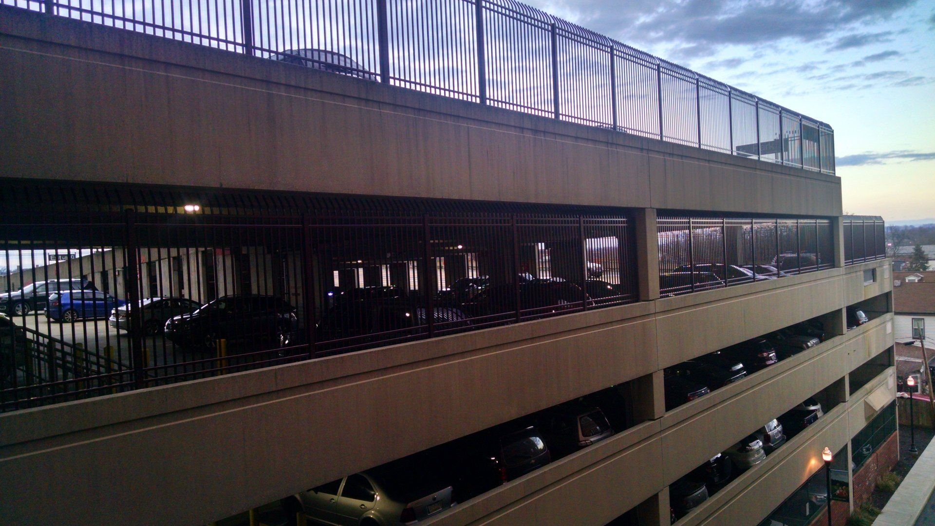 Multi-story parking garage with cars, dusk setting.