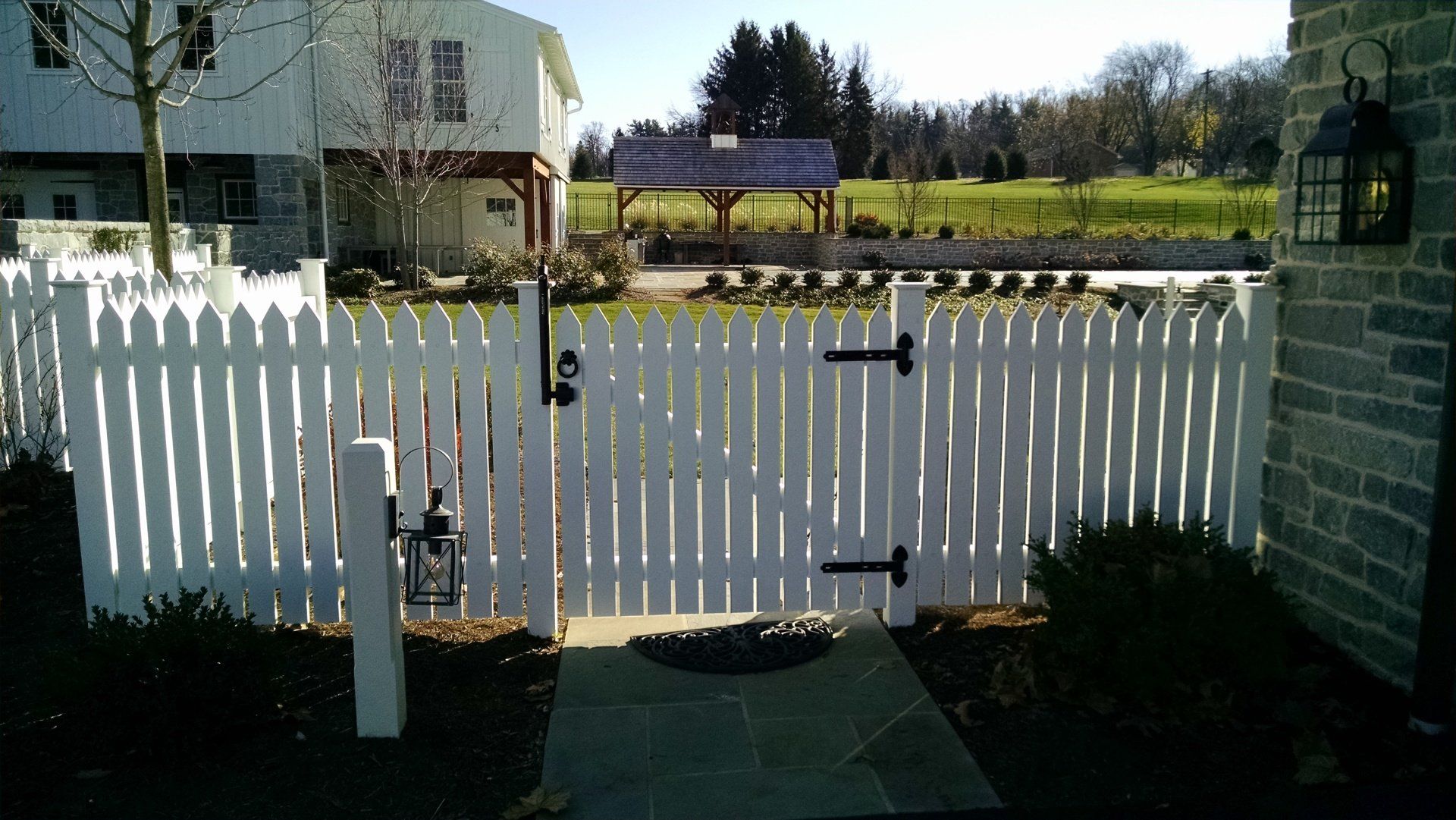 White picket fence with a gate, leading to a path and a building. Sunny outdoor setting in Lititz, PA.