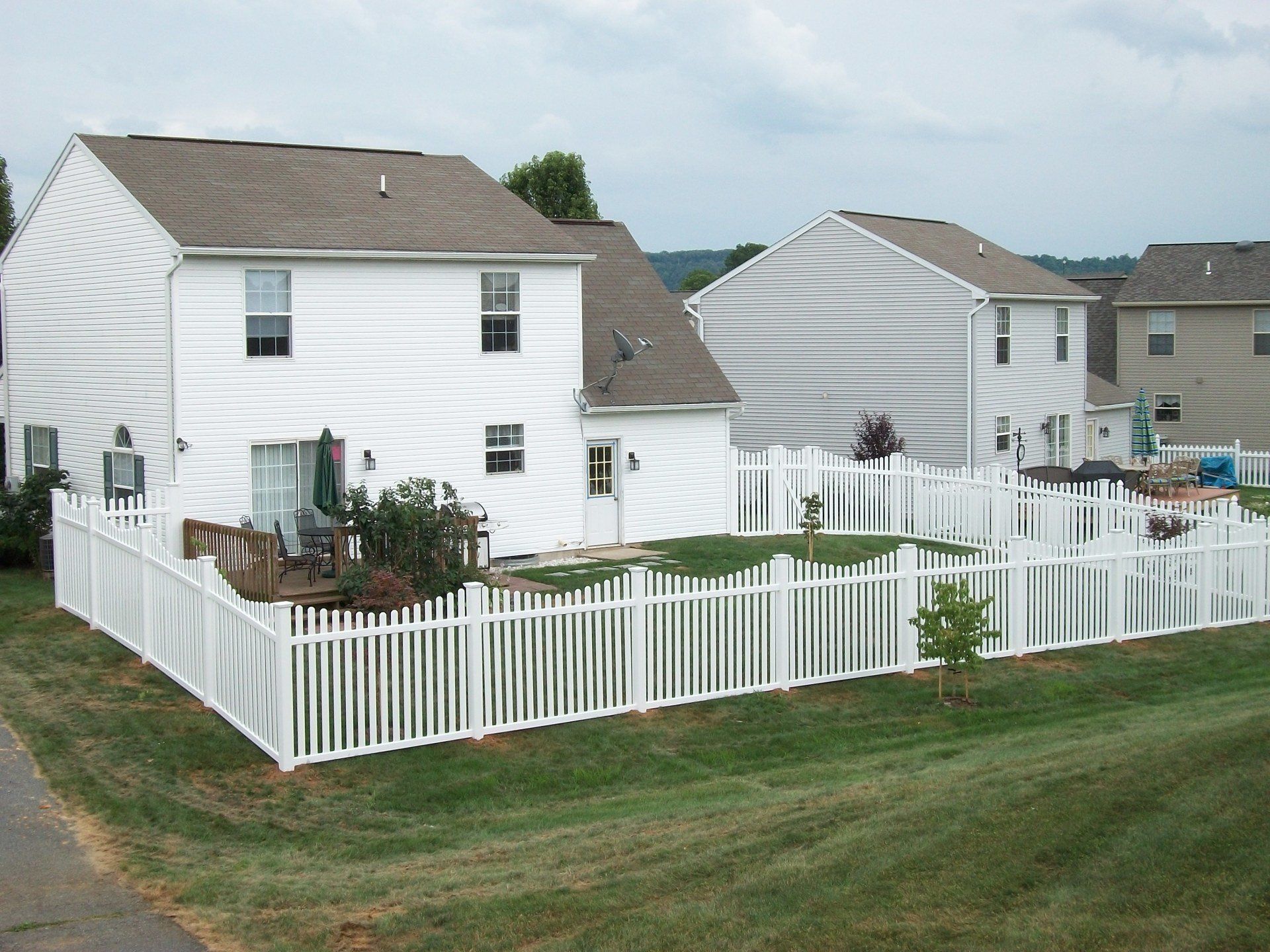White house with picket fence in suburban yard.