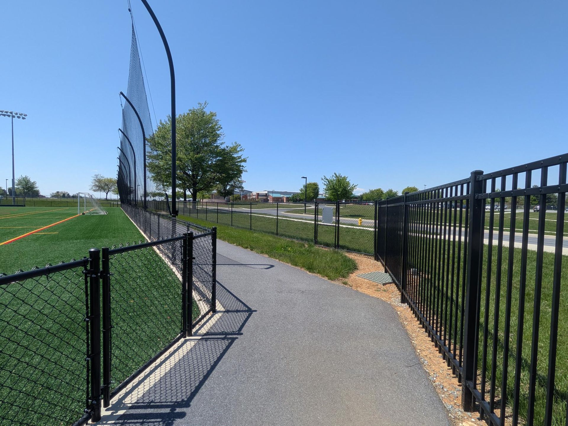 athletic field fencing along paved walking path behind turf football field in Lititz PA