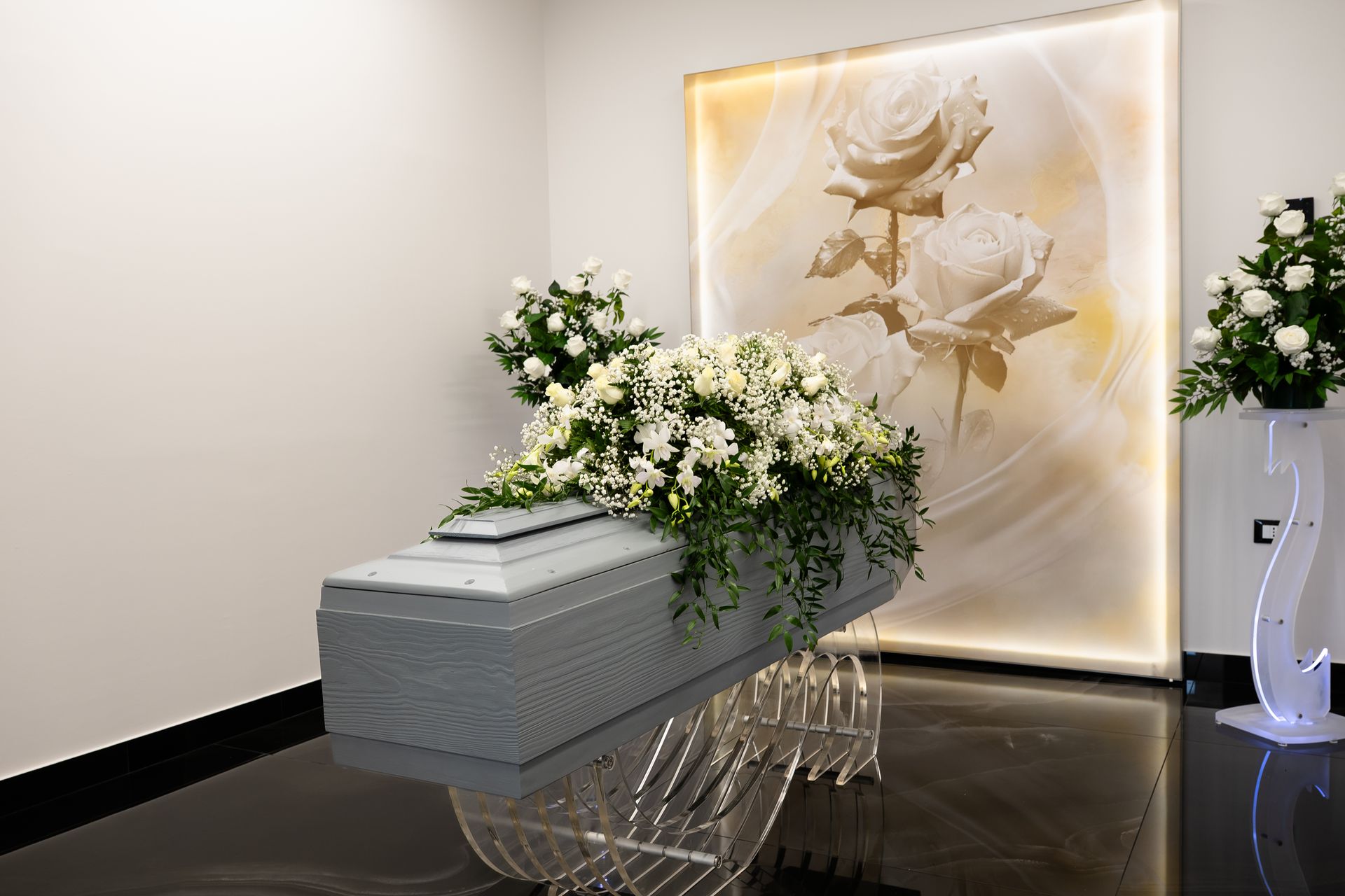 Bara bianca adornata con fiori in un'agenzia di pompe funebri, composizione floreale e un'opera d'arte raffigurante una rosa.