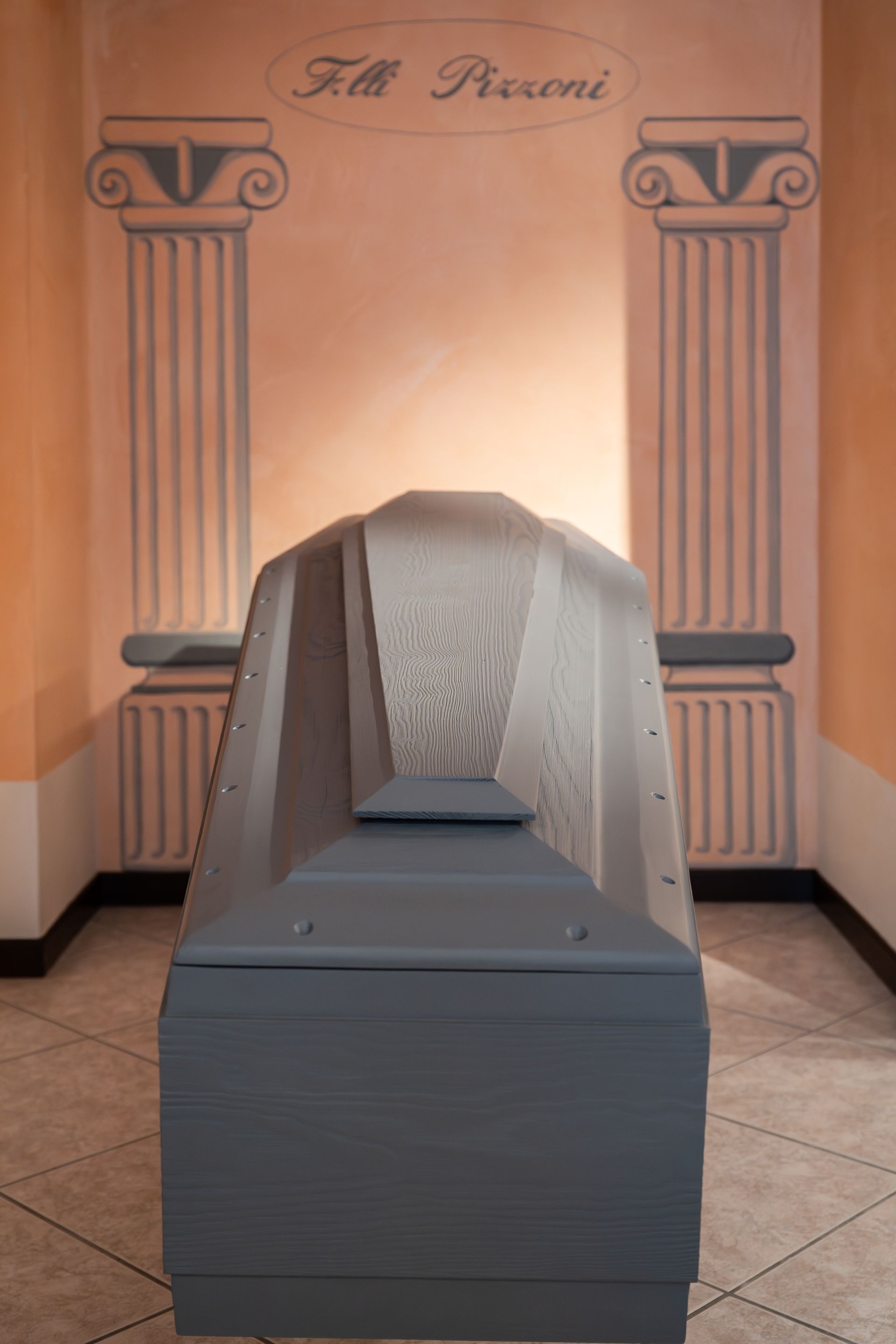 Bara grigia in una stanza con colonne dipinte e testo sopra.