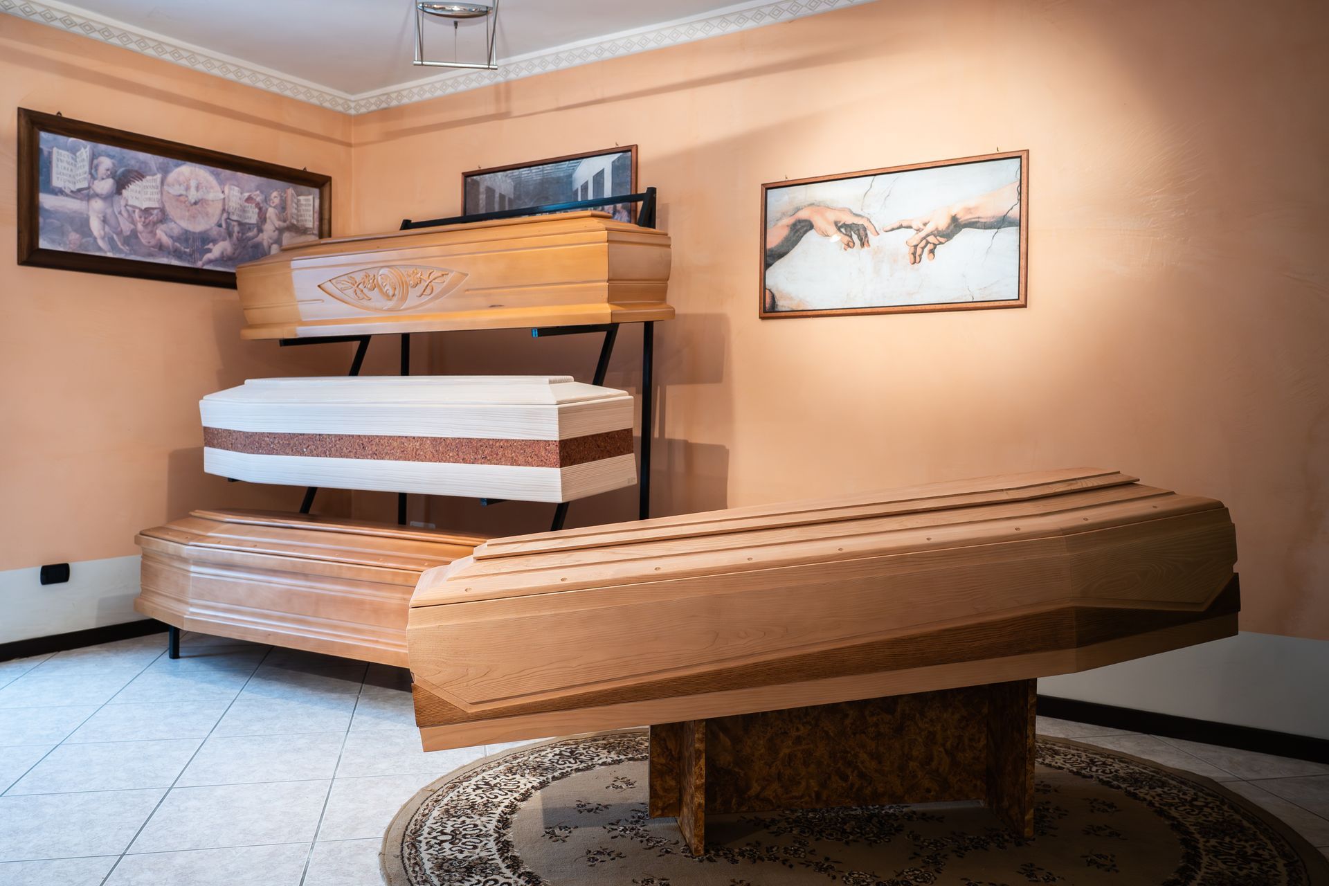 Esposizione di bare in una stanza, con stili e tonalità di legno diversi, con opere d'arte alle pareti.