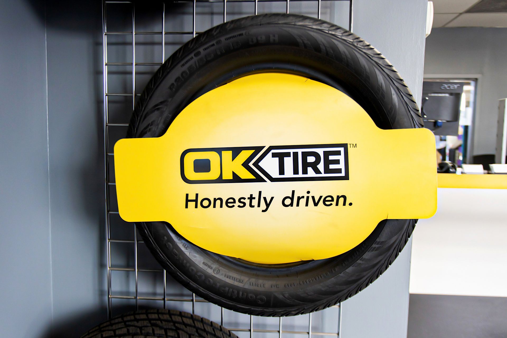 OK Tire logo on a yellow sign over a tire display. 