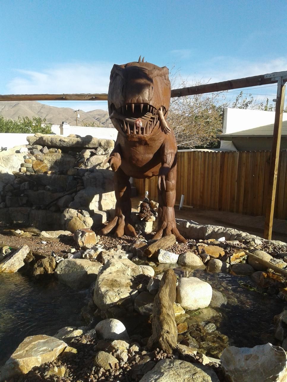 A statue of a dinosaur is surrounded by rocks and water