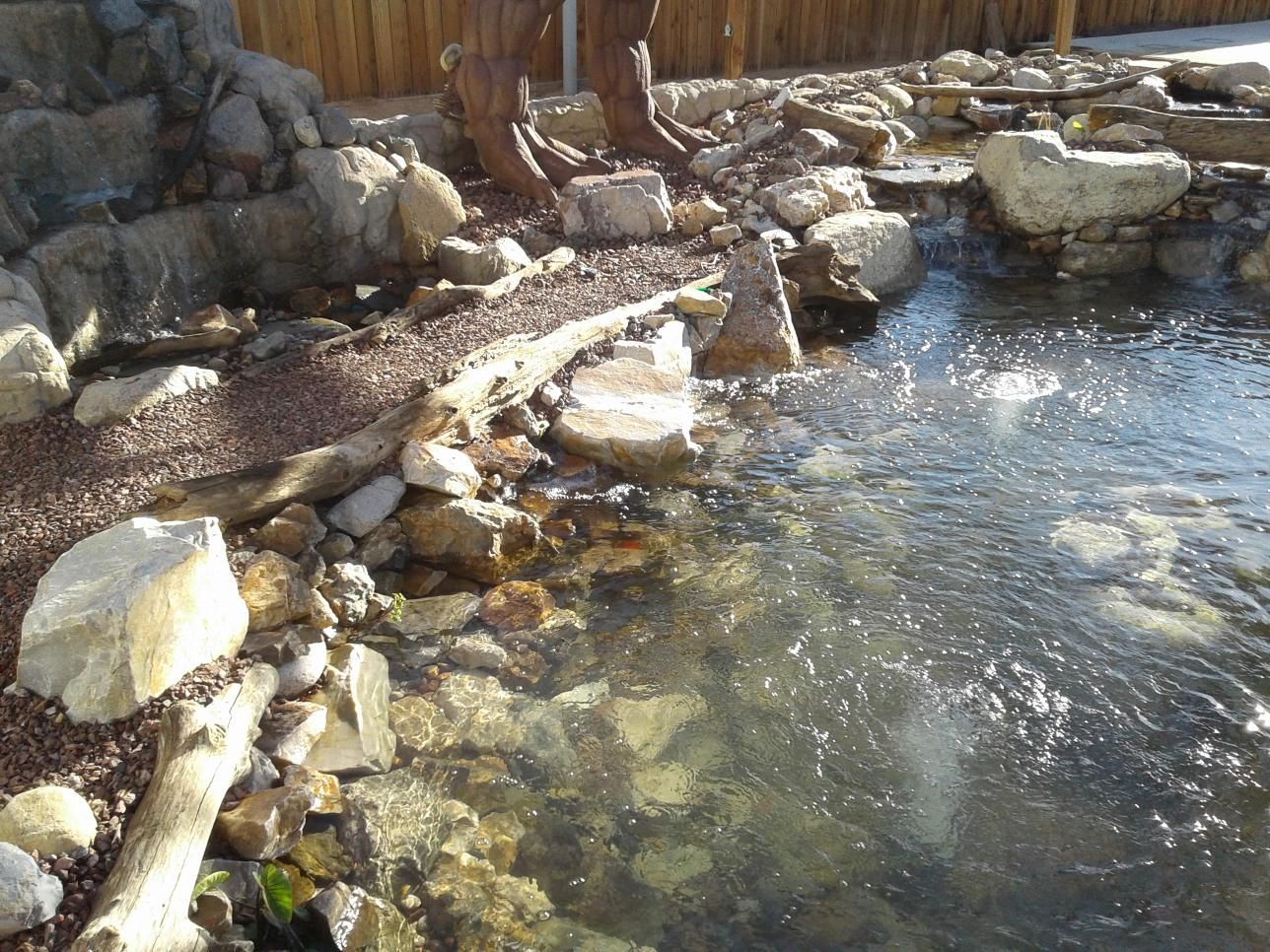 A pond surrounded by rocks and a wooden fence
