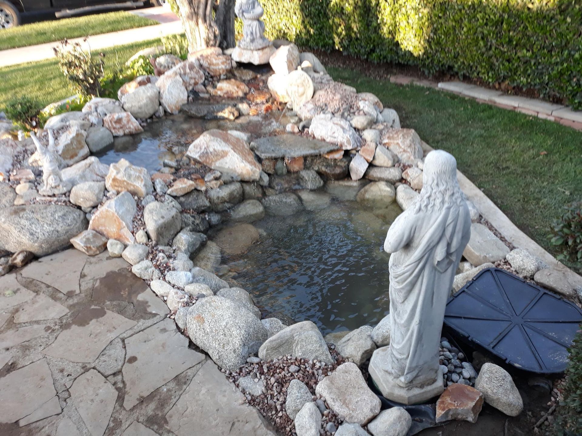 A statue of jesus is standing next to a pond