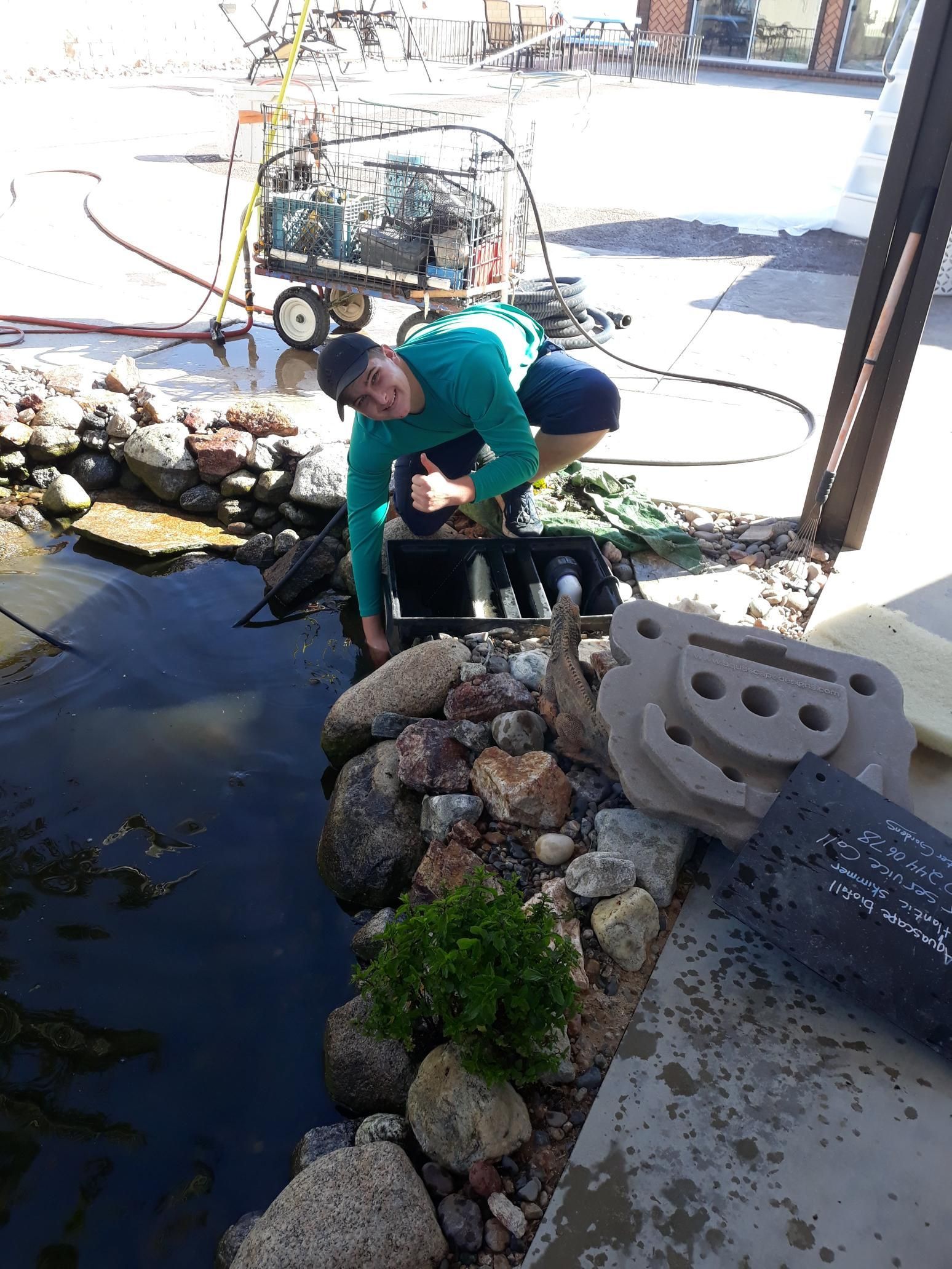A man is working on a pond with a hose.
