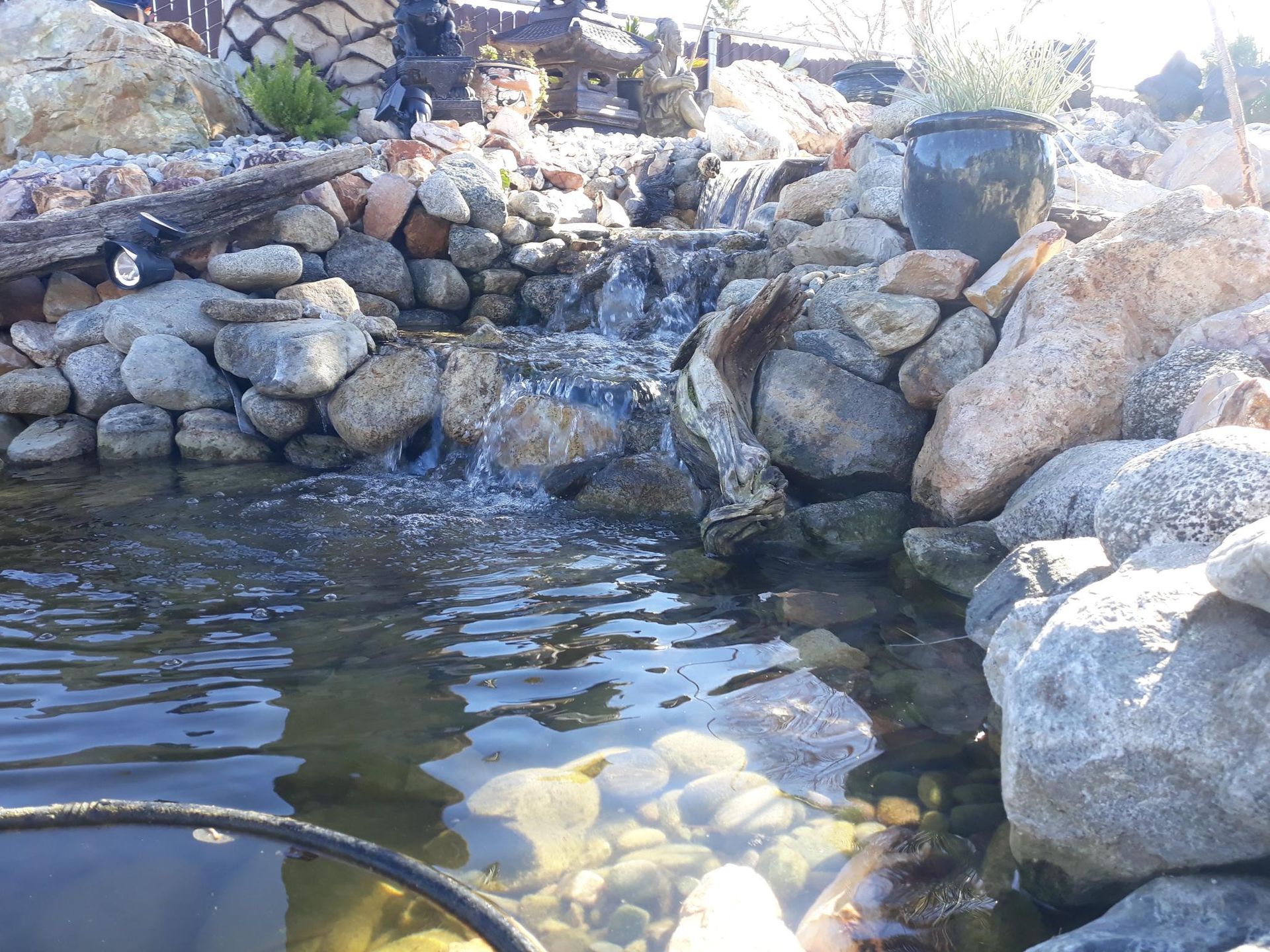 A waterfall is surrounded by rocks in a pond