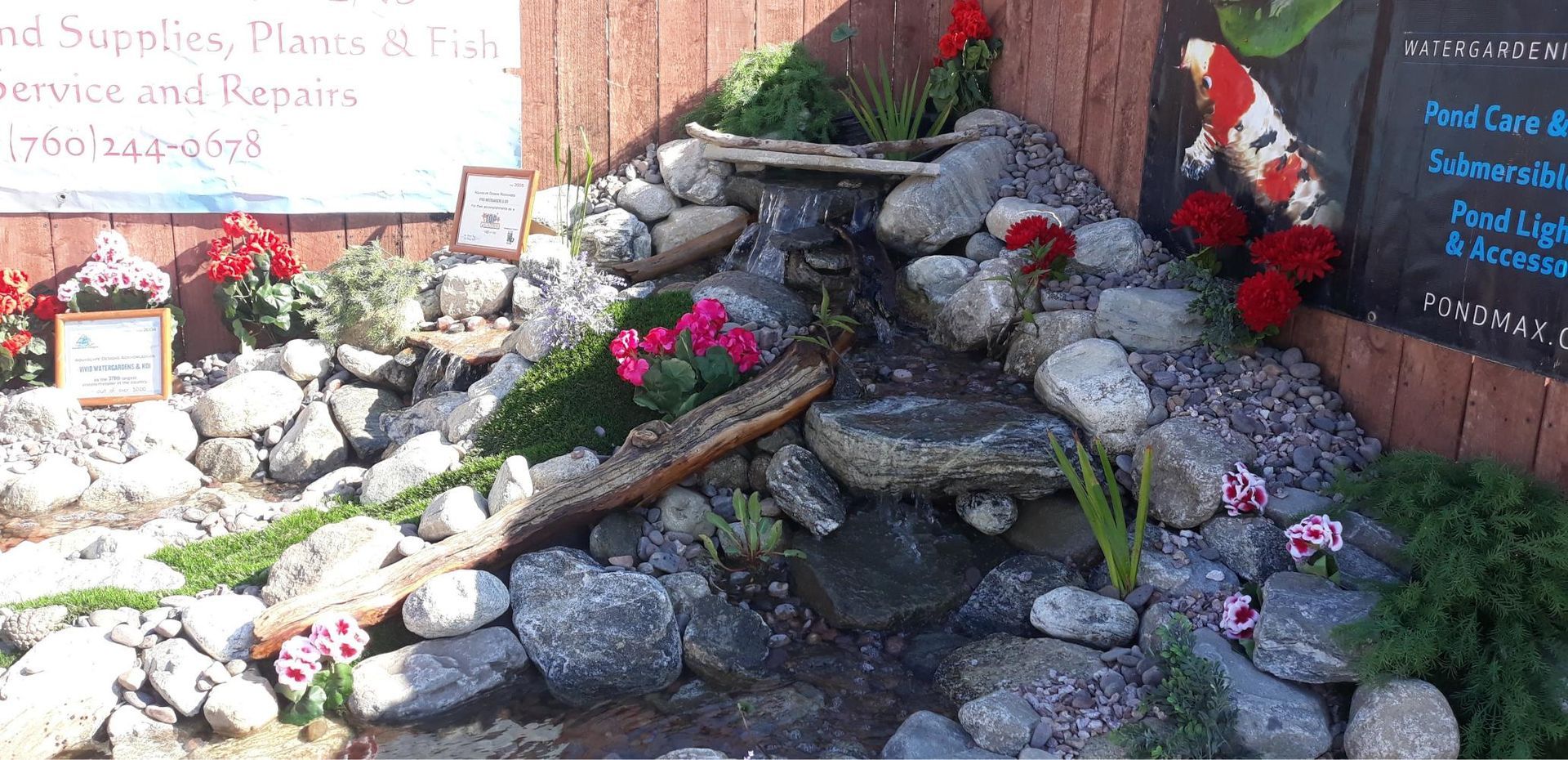 A rock garden with flowers and a sign in the background.