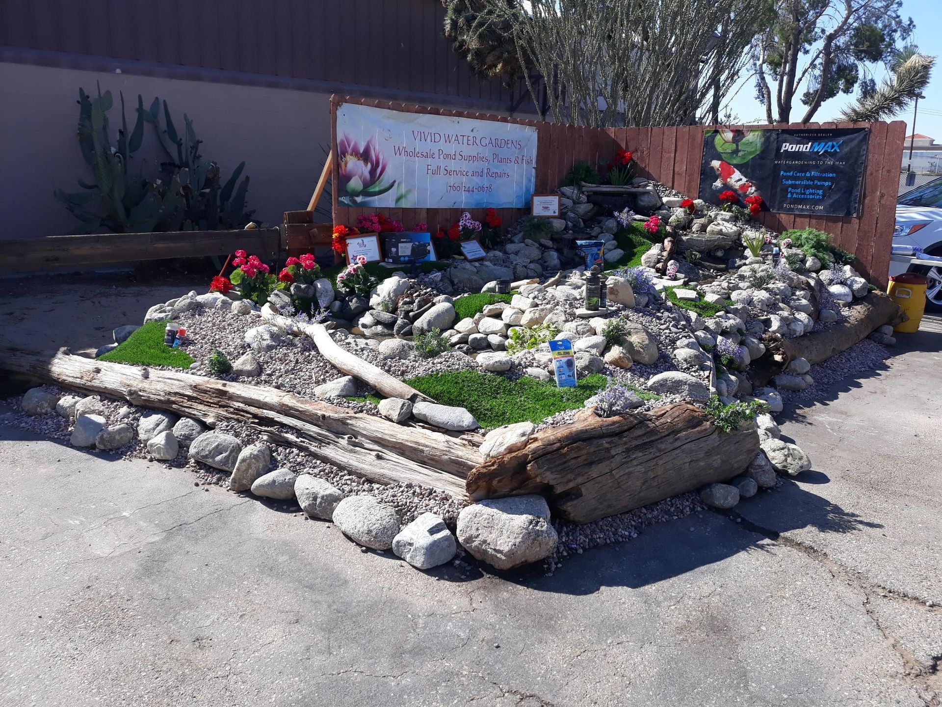 A rock garden with flowers and a sign in the background